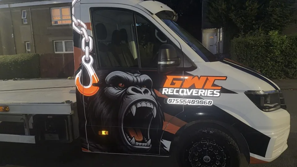 Driver-side view of the recovery truck with black and orange graphics and a large gorilla illustration.