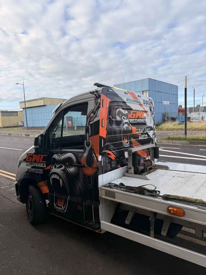 Three-quarter view of a recovery truck with black and orange cab graphics and a large gorilla illustration.