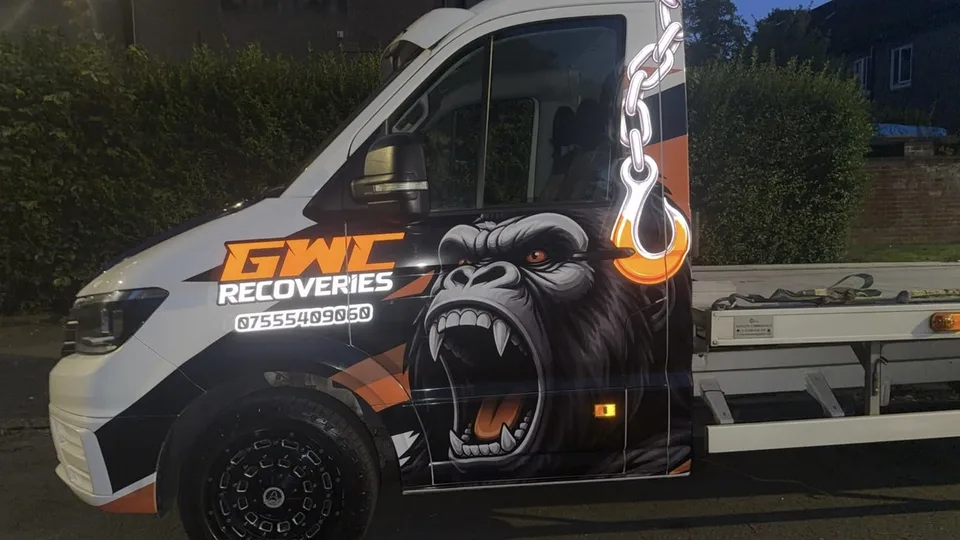Passenger-side view of the recovery truck with gorilla, chain and hook graphics across the cab.