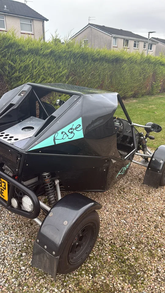 Close-up of turquoise Rage lettering on the side panel of a black rage buggy.