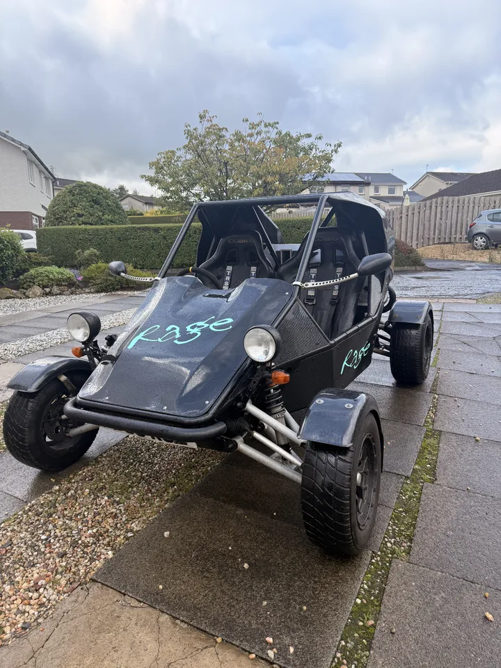 Front three-quarter view of a black rage buggy with turquoise Rage lettering on the bonnet.