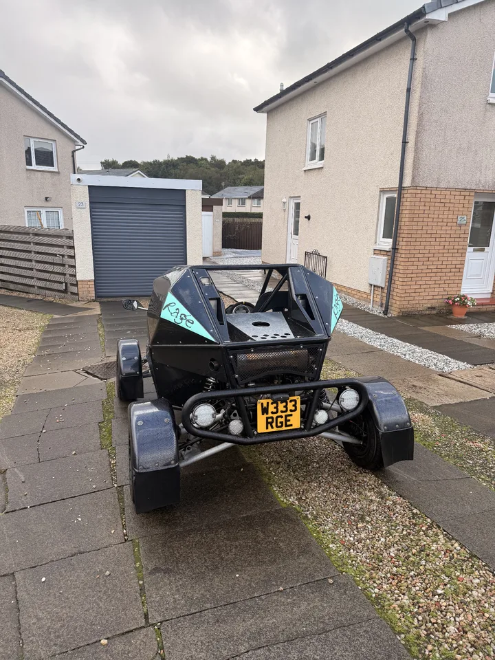 Rear view of a black rage buggy with turquoise Rage lettering on both rear-side panels.