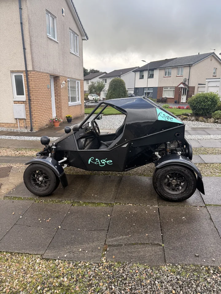 Side view of a black rage buggy with turquoise Rage lettering and an accent panel.