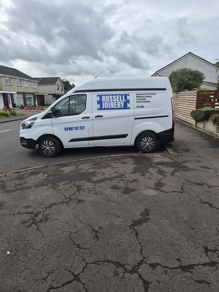 Russell Joinery white van with blue-and-white vehicle graphics, contact details and listed services.