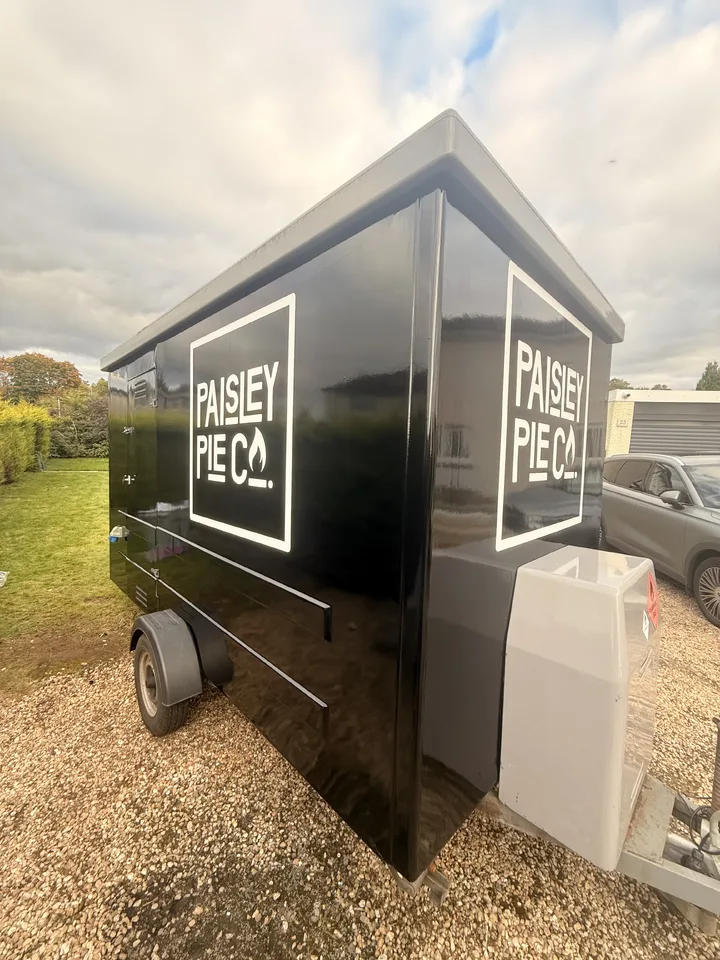 Angled view of the completed black trailer showing white Paisley Pie Co logos on the side and front panels.