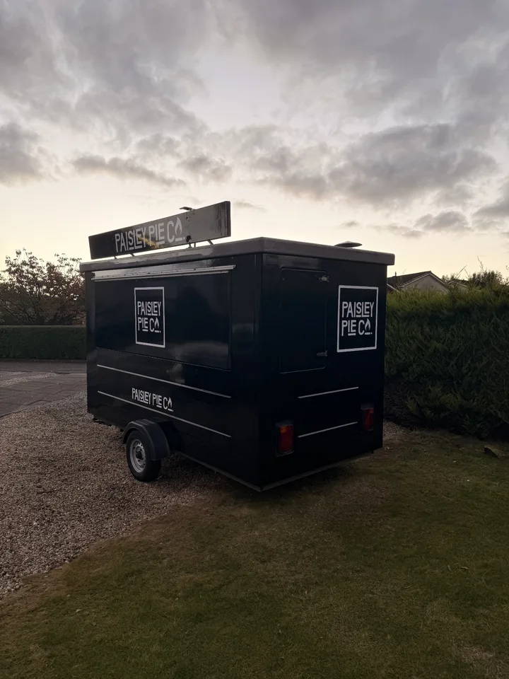 Serving side and rear of the finished black Paisley Pie Co trailer with white logo graphics.