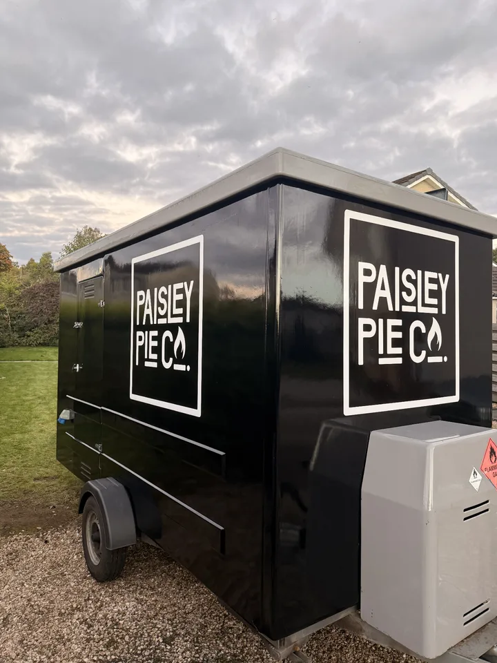 Close view of white Paisley Pie Co logos against the black wrap on the side and front of the trailer.